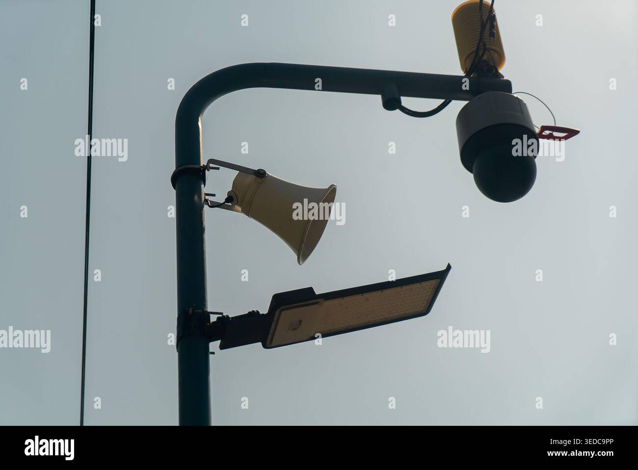 Questa immagine presenta un lampione combinato con un altoparlante montato su un palo, che mette in evidenza le infrastrutture urbane e la tecnologia di comunicazione in un Foto Stock