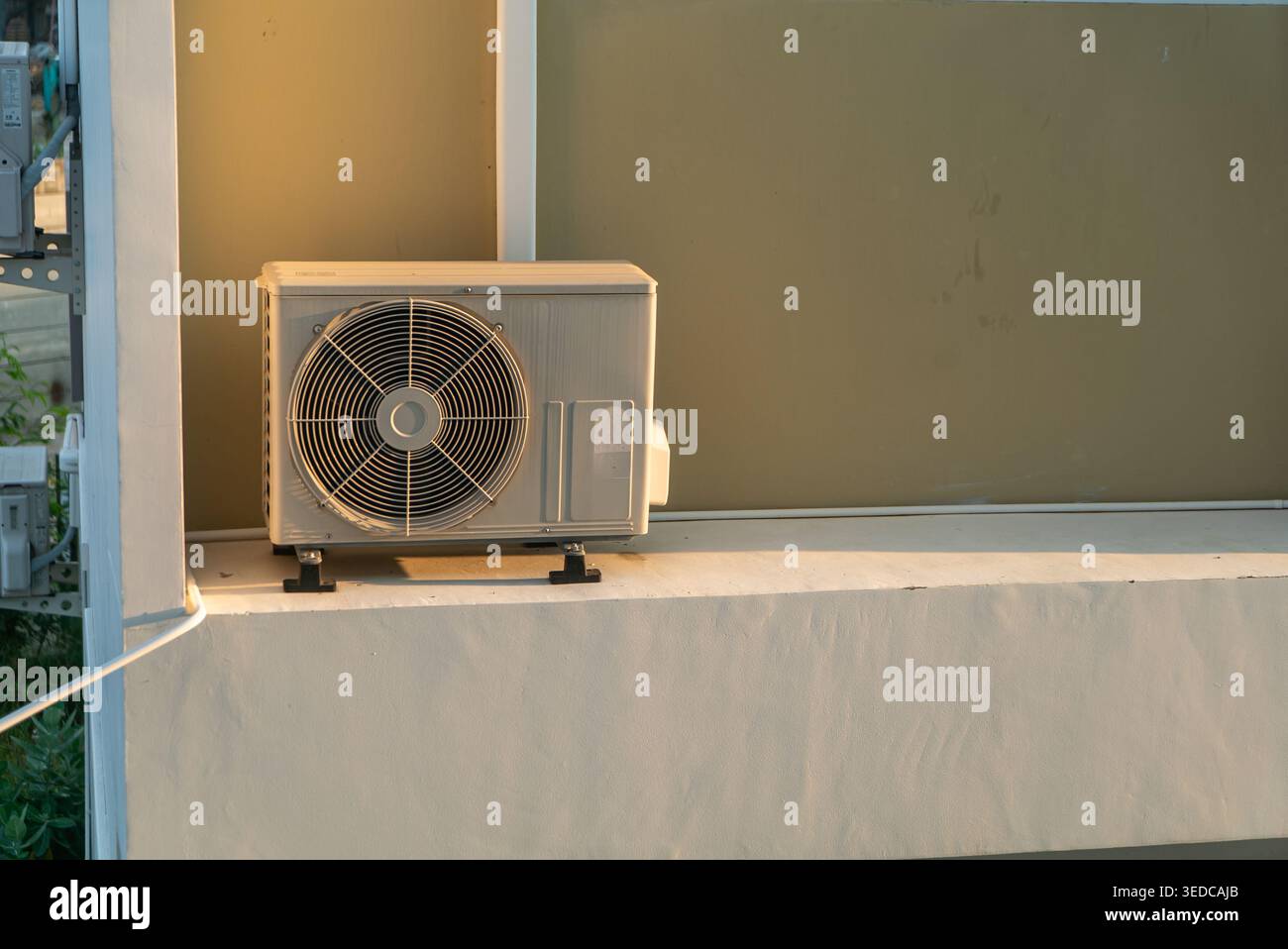 Un'unità di aria condizionata esterna solitaria appoggiata su una parete, che mette in mostra la tecnologia moderna progettata per rinfrescare gli spazi durante il clima caldo. Perfetto per Foto Stock