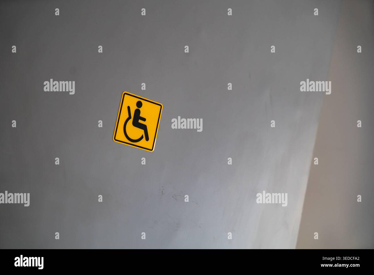 Un chiaro e semplice cartello per i servizi igienici, con sfondo giallo con il simbolo di una sedia a rotelle, che promuove la consapevolezza e l'inclusività nella spa pubblica Foto Stock