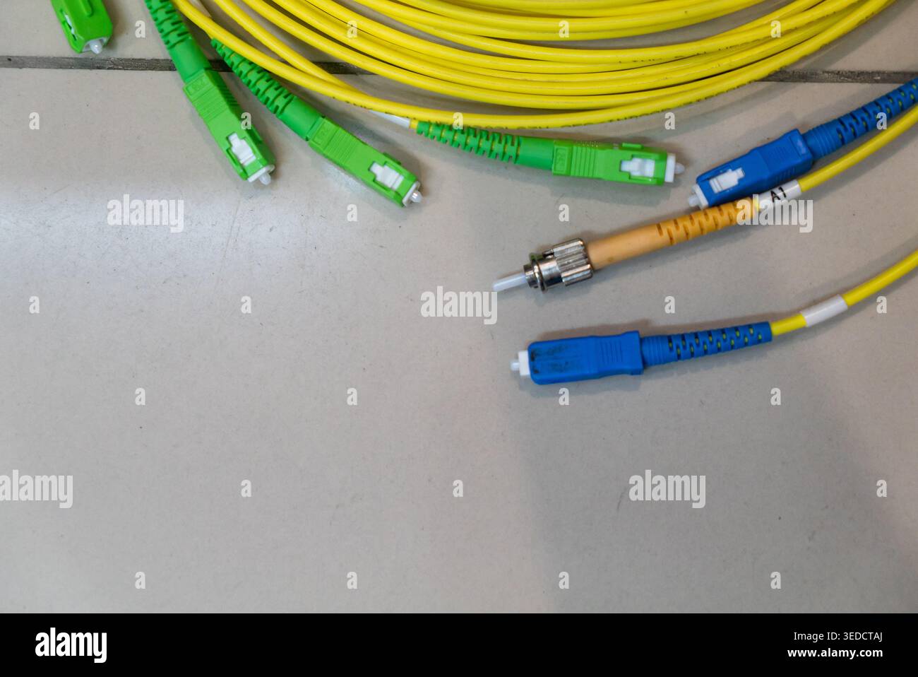 Vista ravvicinata dei cavi in fibra ottica dai colori giallo, blu e verde. Questi cavi svolgono un ruolo cruciale nel trasferimento e nella comunicazione dei dati ad alta velocità Foto Stock