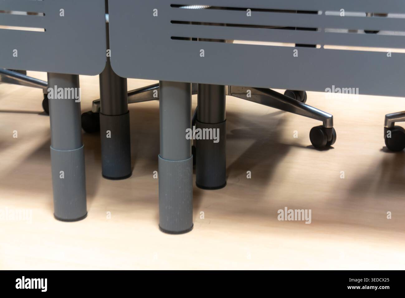 Una moderna scrivania da ufficio con un elegante design grigio e gambe robuste, perfetta per uno spazio di lavoro professionale che enfatizza funzionalità e comfort. Foto Stock