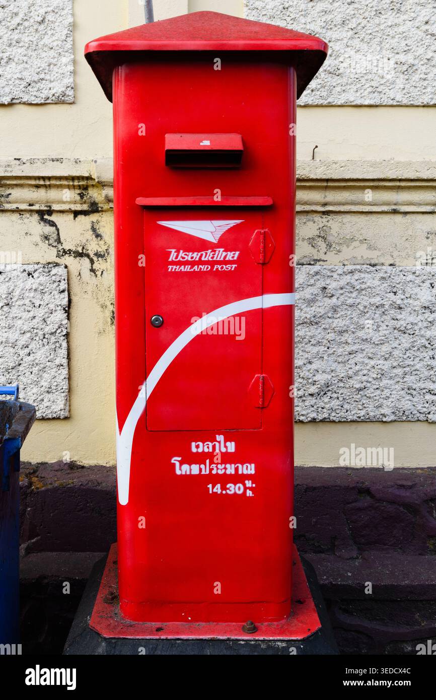 Colorata, rossa, dipinta, cassetta postale pubblica vintage su un marciapiede a Phuket, Thailandia, con la parola "mail" scritta nella scrittura abugida del langu tailandese Foto Stock