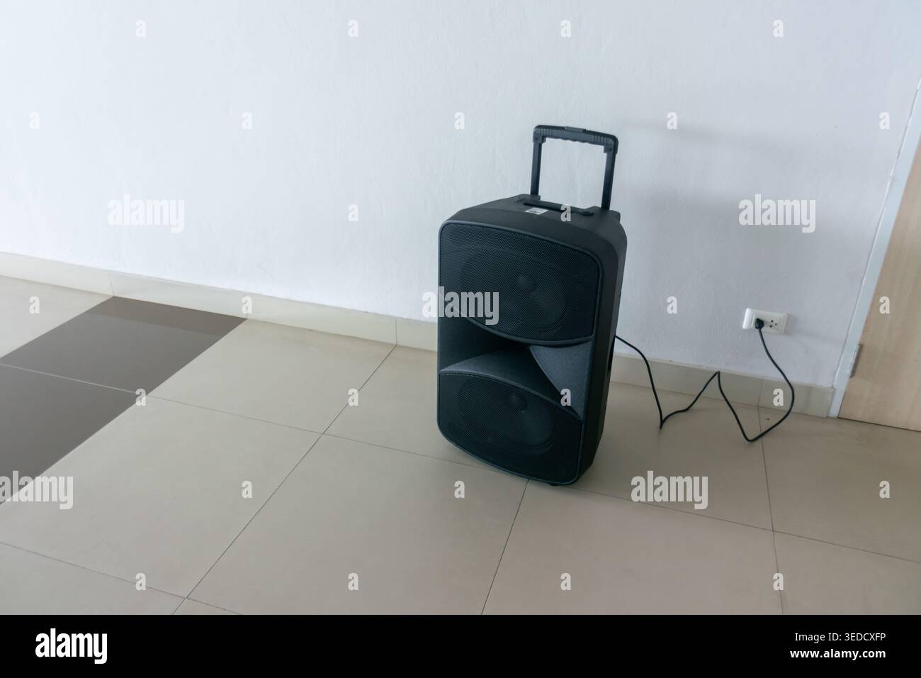 Altoparlante musicale portatile posizionato sul pavimento di una sala moderna, che presenta un design elegante e funzionalità audio, ideale per eventi o per noi personali Foto Stock