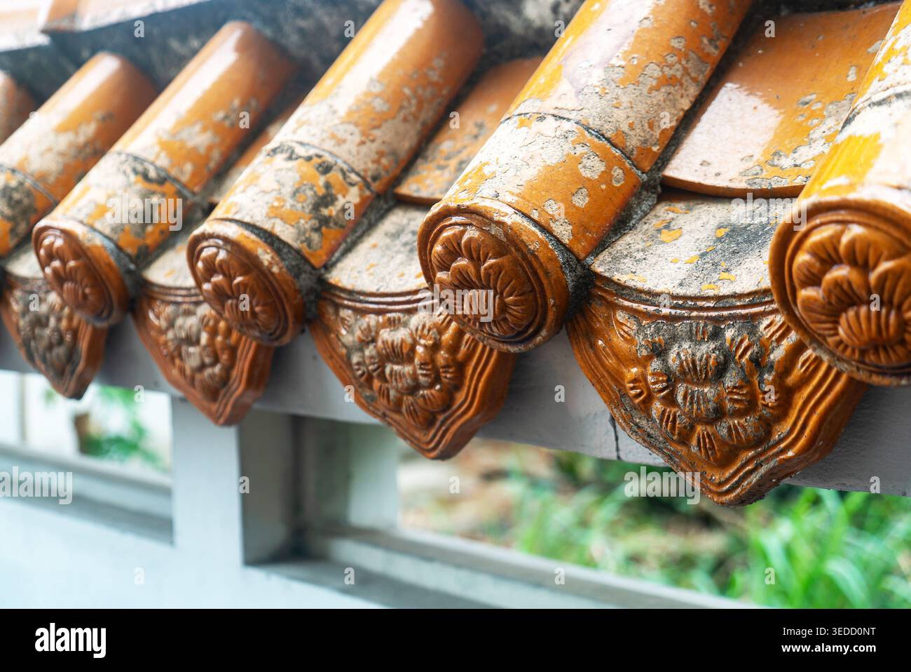 Primo piano di tegole splendidamente lavorate che mostrano intricati motivi floreali. La finitura rustica arancione mette in risalto la consistenza e l'arte del tradit Foto Stock