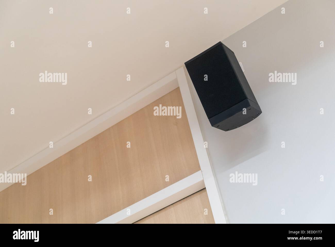 Un elegante altoparlante nero montato su una parete bianca che migliora il design moderno degli interni dello spazio e offre un audio di qualità per un'esperienza coinvolgente Foto Stock