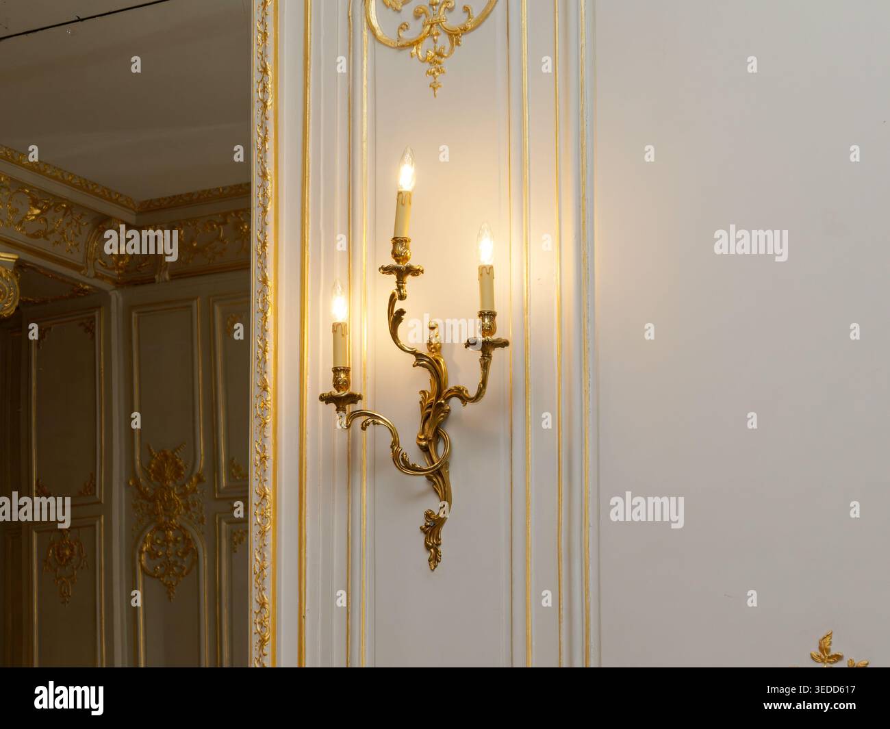 Elegante applique dorata e raffinati dettagli decorativi in un lussuoso interno classico francese. Foto Stock