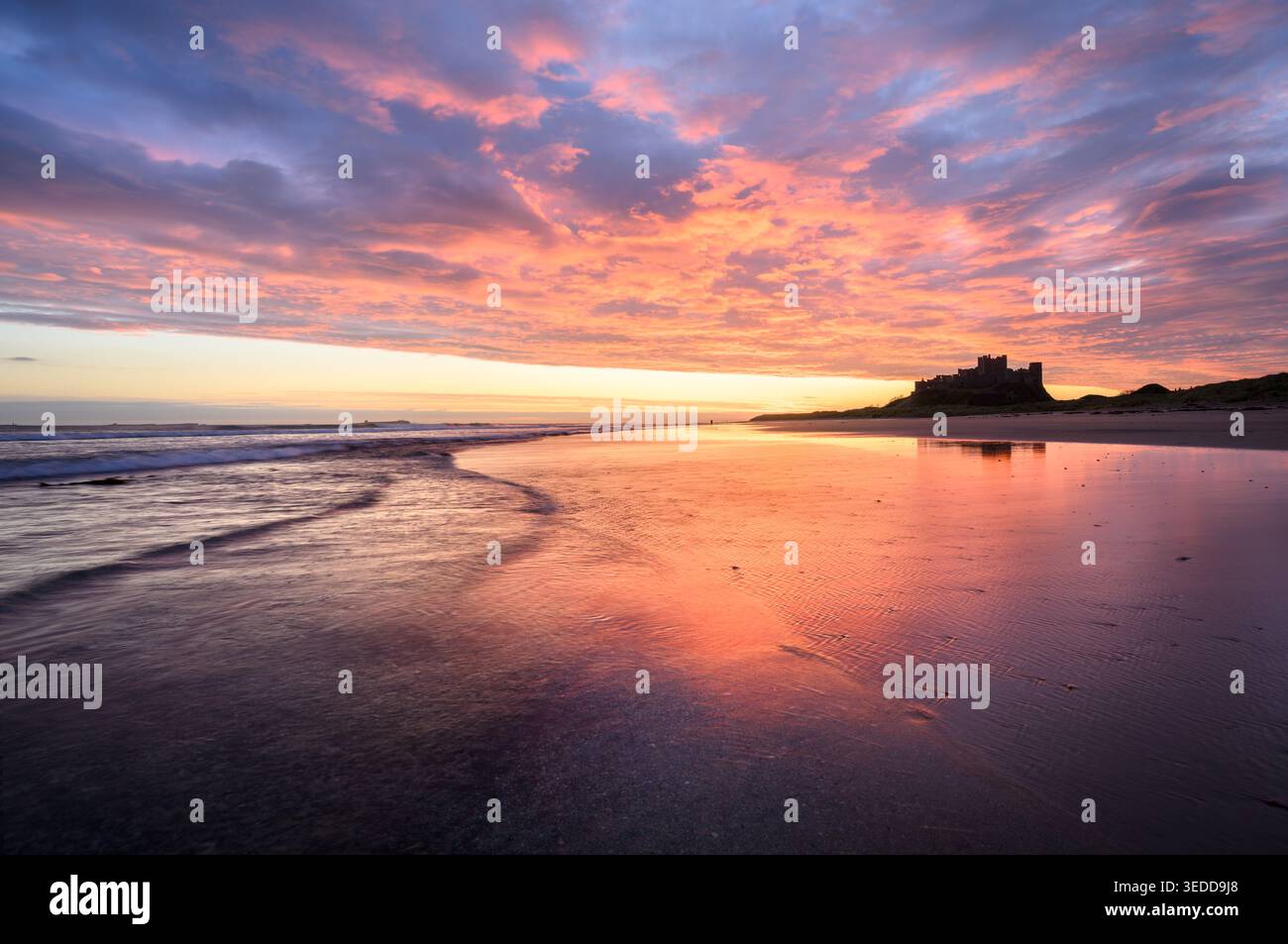 Spettacolare alba sulla spiaggia al castello di Bamburgh sulla costa del Northumberland, Regno Unito. Foto Stock