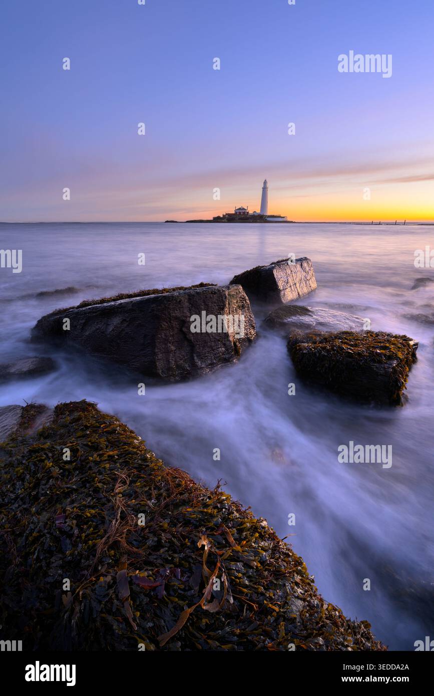 Faro di St. Marys con rocce nell'oceano all'ora blu, Whitley Bay, Tyne & Wear, Regno Unito. Foto Stock