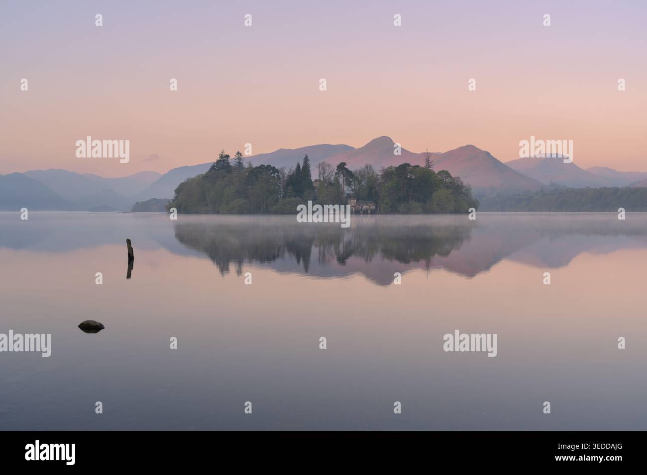 Tranquille vedute mattutine dell'isola di Derwent e delle montagne Catbells che si riflettono in acque calme e nebbiose, Derwentwater, Lake District, Regno Unito. Foto Stock