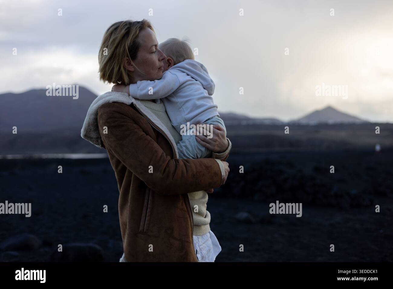 Autentico momento d'amore e di connessione tra madre e bambino vicino al mare Foto Stock