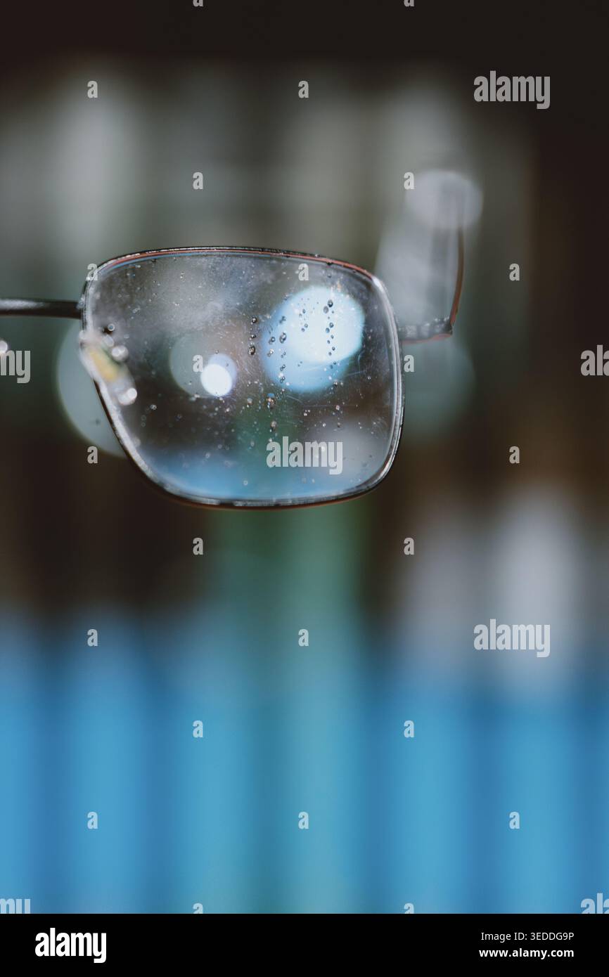 Primo piano di un obiettivo per occhiali polveroso e leggermente danneggiato con sfondo bokeh e messa a fuoco morbida Foto Stock