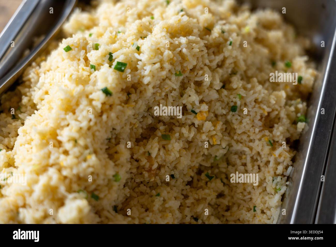 Gustoso riso fritto con contorno alle erbe verdi cucinato alla perfezione servito caldo in un grande contenitore di metallo a buffet per un delizioso pasto prepa Foto Stock