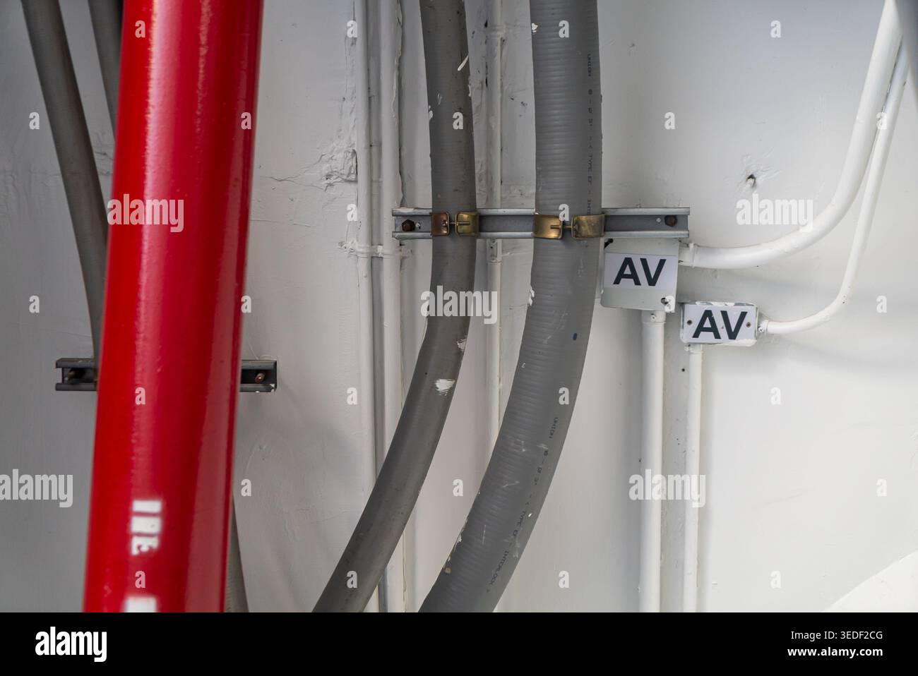 Vista ravvicinata di tubi e tubi flessibili industriali in una struttura. L'immagine mostra i componenti rossi e grigi, evidenziando connessioni e installazioni con Foto Stock