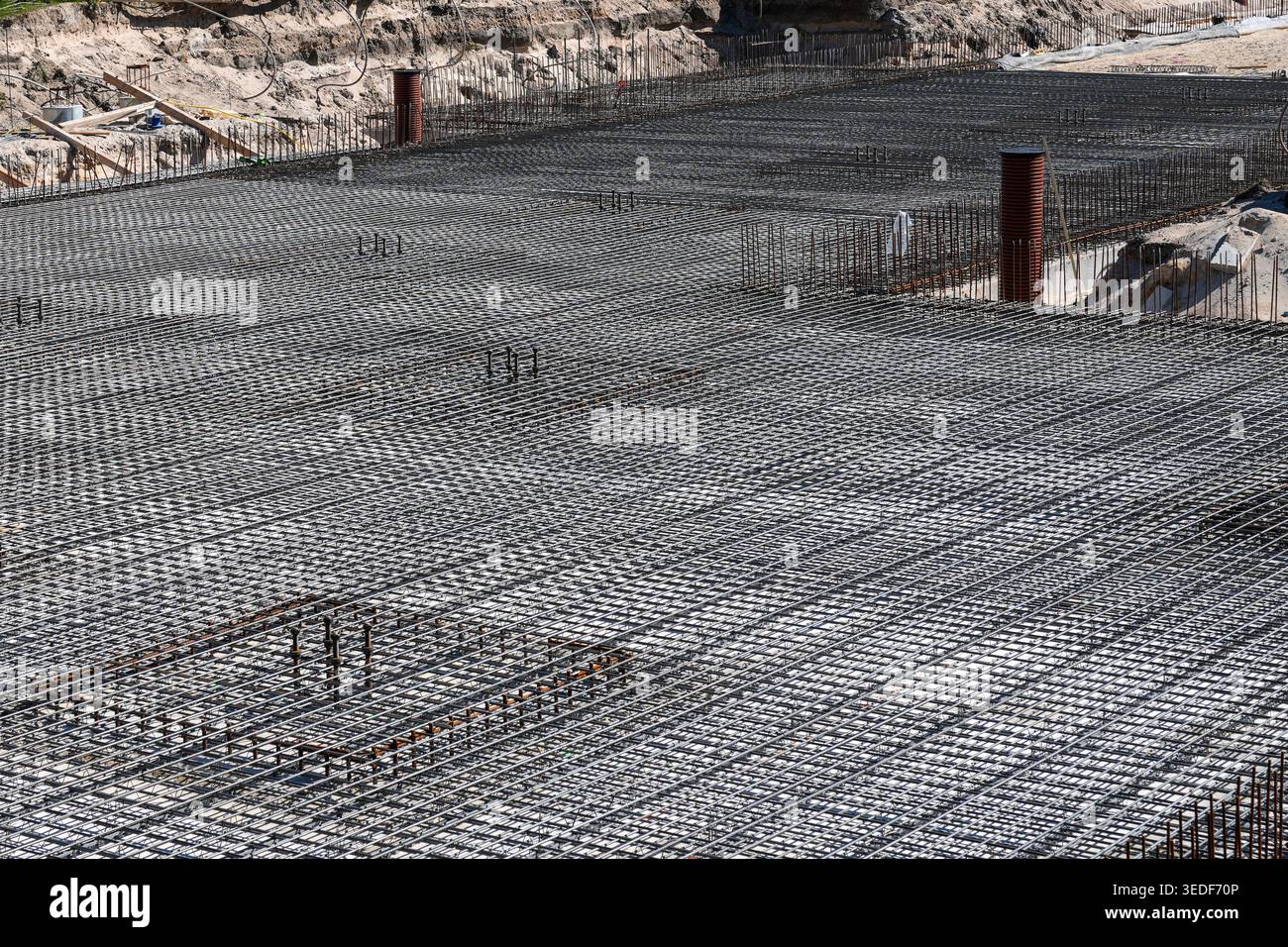 Ampia griglia in acciaio per armature disposte per la fondazione di solette in calcestruzzo, che mostra precisione ingegneristica, lavori di messa a terra e moderni costruttori di cantieri Foto Stock