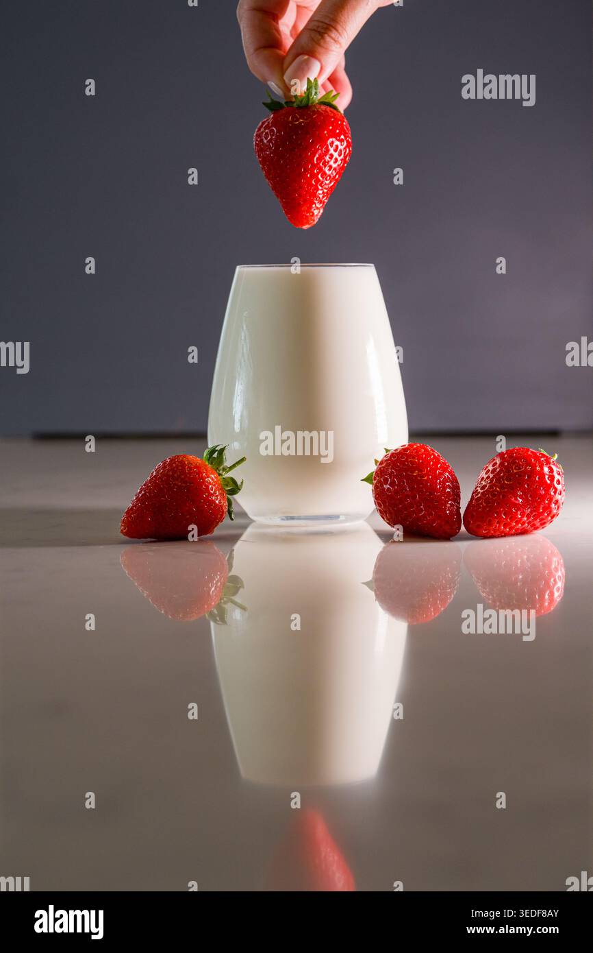 Versare a mano la fragola nel concetto di dessert cremoso. Foto Stock