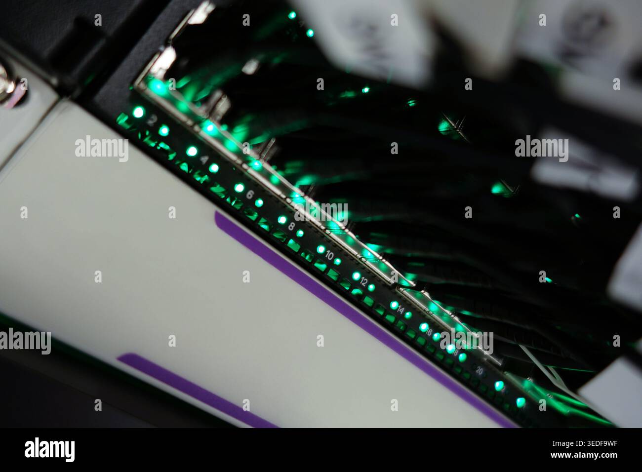 Vista ravvicinata di una scheda a circuito stampato high-tech con LED verdi brillanti. Il design complesso mette in mostra tecnologia avanzata e componenti elettronici Foto Stock