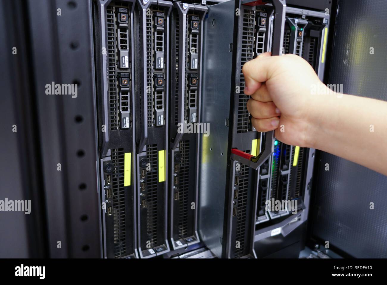 Immagine ravvicinata di una mano che apre un rack server in un data center, che illustra i processi di gestione dei server e manutenzione della tecnologia. Foto Stock