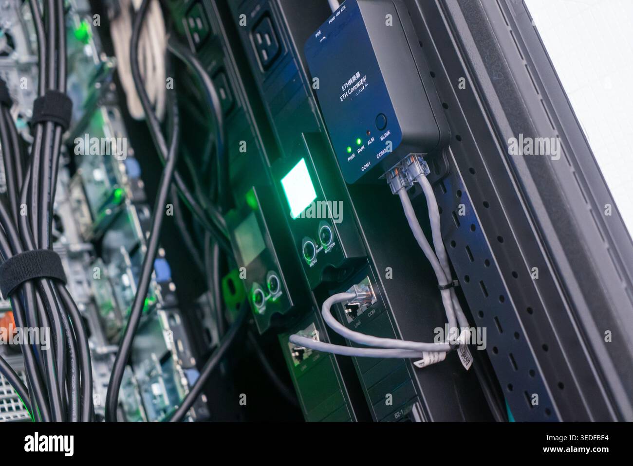 Vista ravvicinata di un server rack che mostra gli strumenti di connettività e i dispositivi di monitoraggio. I cavi si intrecciano quando gli indicatori si accendono, sottolineando la tecnologia" Foto Stock