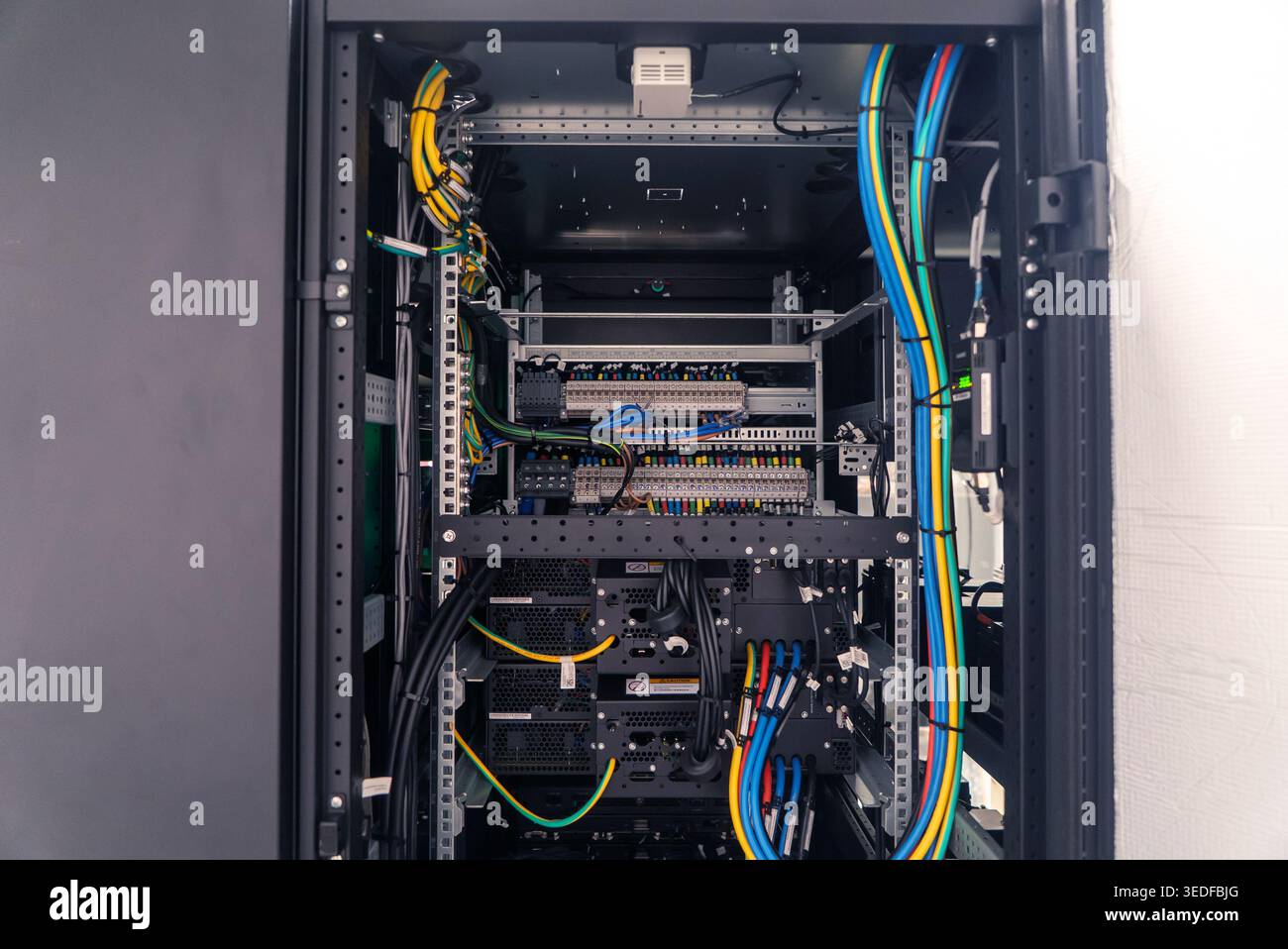 Vista dettagliata di un server rack per data center pieno di cavi di rete colorati, che mostra la complessità delle moderne telecomunicazioni e gestione dei dati Foto Stock