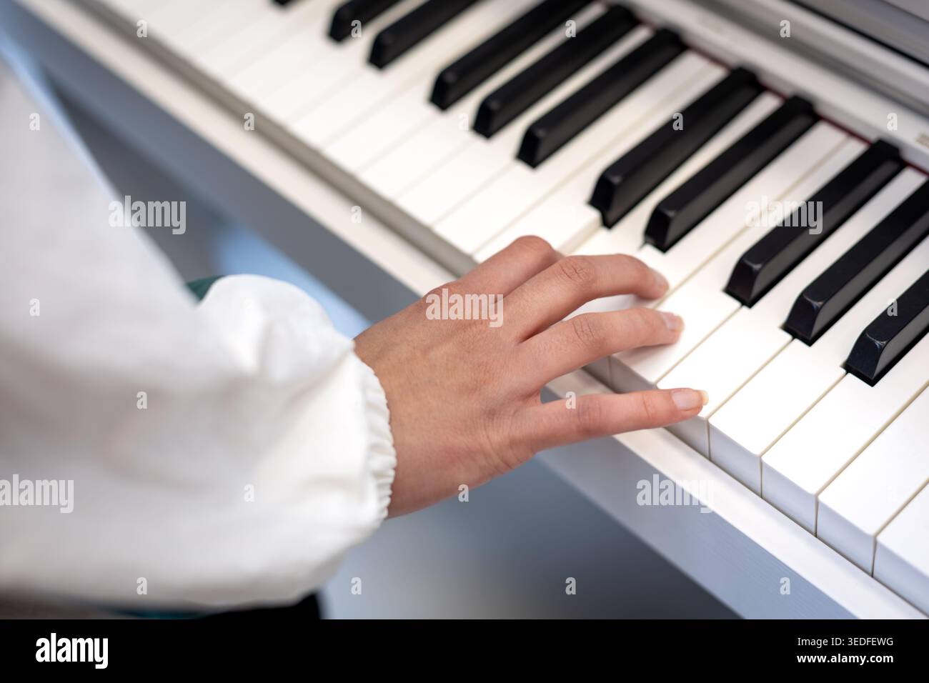 Primo piano con tastiera per pianoforte a mano. Primo piano di una mano premendo i tasti del piano, mostrando la pratica musicale, l'apprendimento, le prestazioni e lo strumento della tastiera Foto Stock