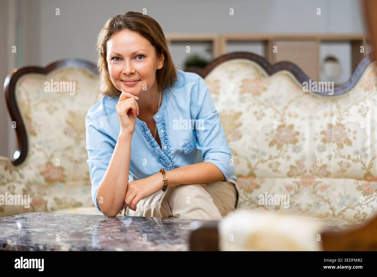 Donna positiva seduta sul divano a casa Foto Stock