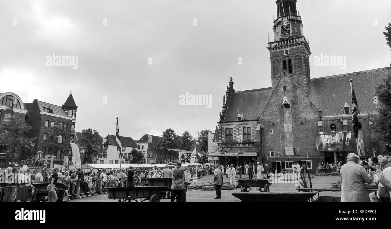 Fotografia in bianco e nero di una vivace piazza del mercato con un mercato del formaggio e la storica torre della chiesa di Alkmaar, Paesi Bassi Foto Stock