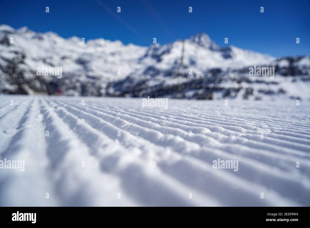 Neve a velluto ondulato su una pista da sci con maestose montagne innevate sotto un cielo azzurro e limpido a la Thuile, Valle d'Aosta, Italia. Foto Stock