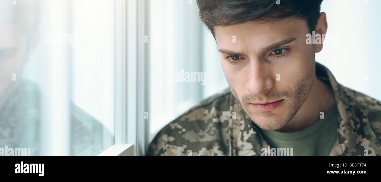 Soldier guarda fuori dalla finestra e riflette durante i momenti tranquilli di pensiero Foto Stock