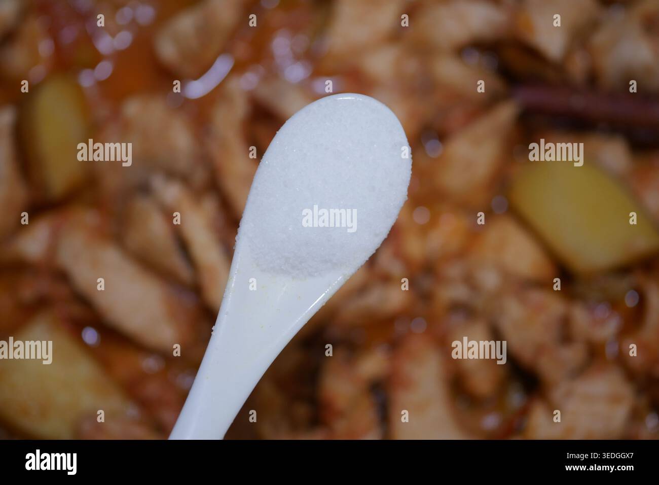 Cucchiaio di sale sopra il pollo cotto e le patate in una pentola Foto Stock