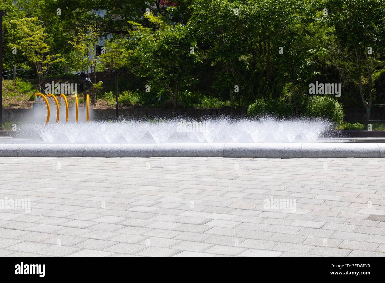 Spruzzo di fontane d'acqua nel moderno parco cittadino durante l'estate Foto Stock