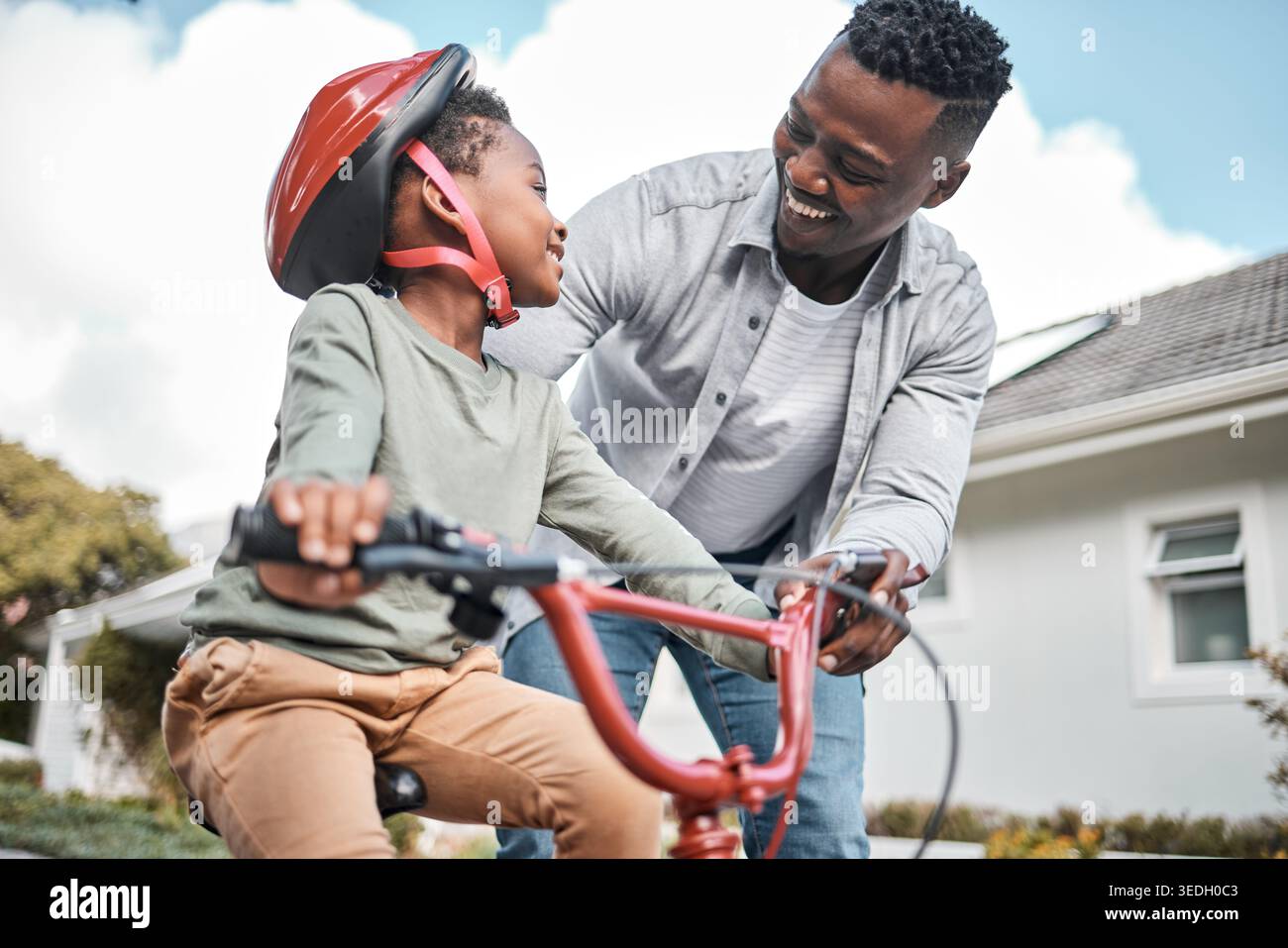 Sorridi, famiglia nera e bambino con bicicletta all'aperto per l'apprendimento, il supporto dei genitori e il legame. Felice, padre e bambino che aiuta con la bici come guida Foto Stock