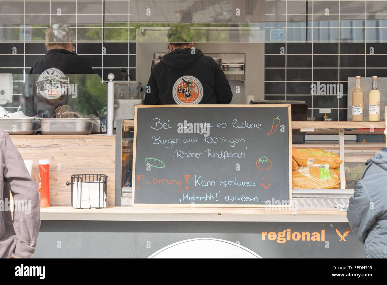 Bancone per camion di cibo di strada con tabellone dei menu. Stile di vita urbano e concetto di servizio fast food. Stand gastronomico all'aperto con i clienti. Cucina di strada e città Foto Stock