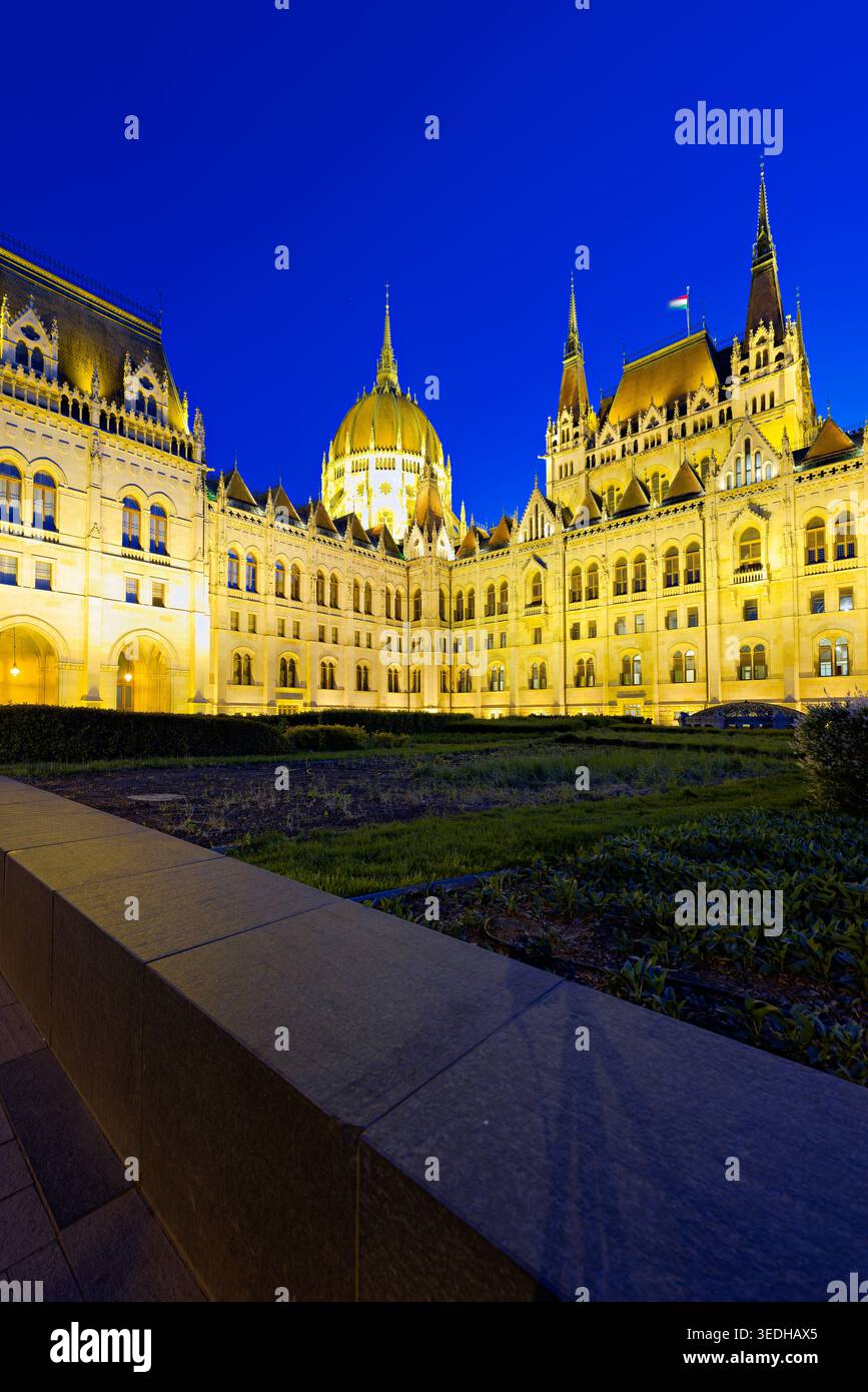 L'edificio del Parlamento di Budapest si erge illuminato contro il cielo serale mentre il sole tramonta, segnando una bella fine della giornata. Foto Stock