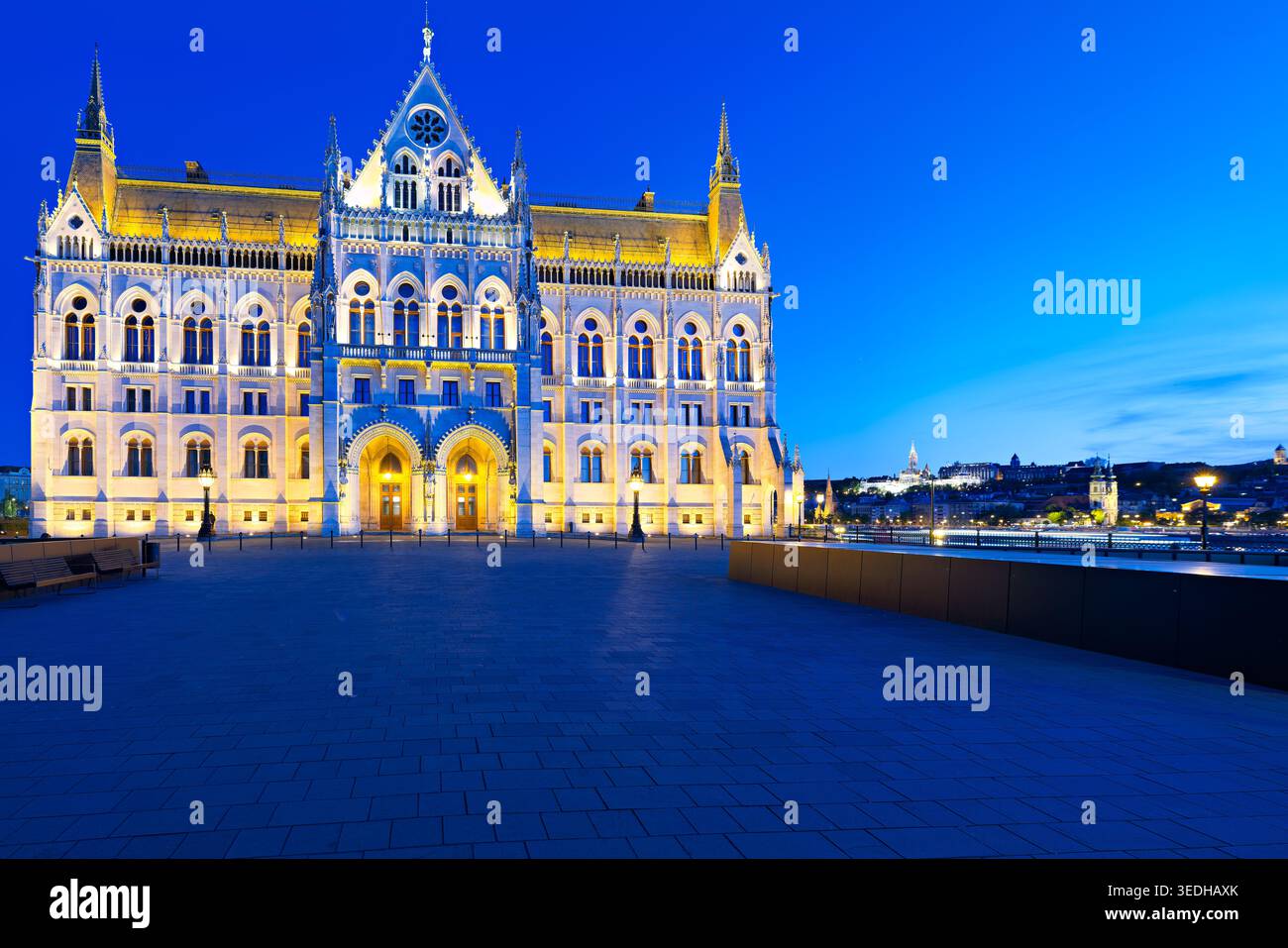 L'edificio del Parlamento di Budapest si erge alto mentre il sole tramonta, proiettando un caldo bagliore sulla sua struttura e sulle aree circostanti. I visitatori godono della vista. Foto Stock