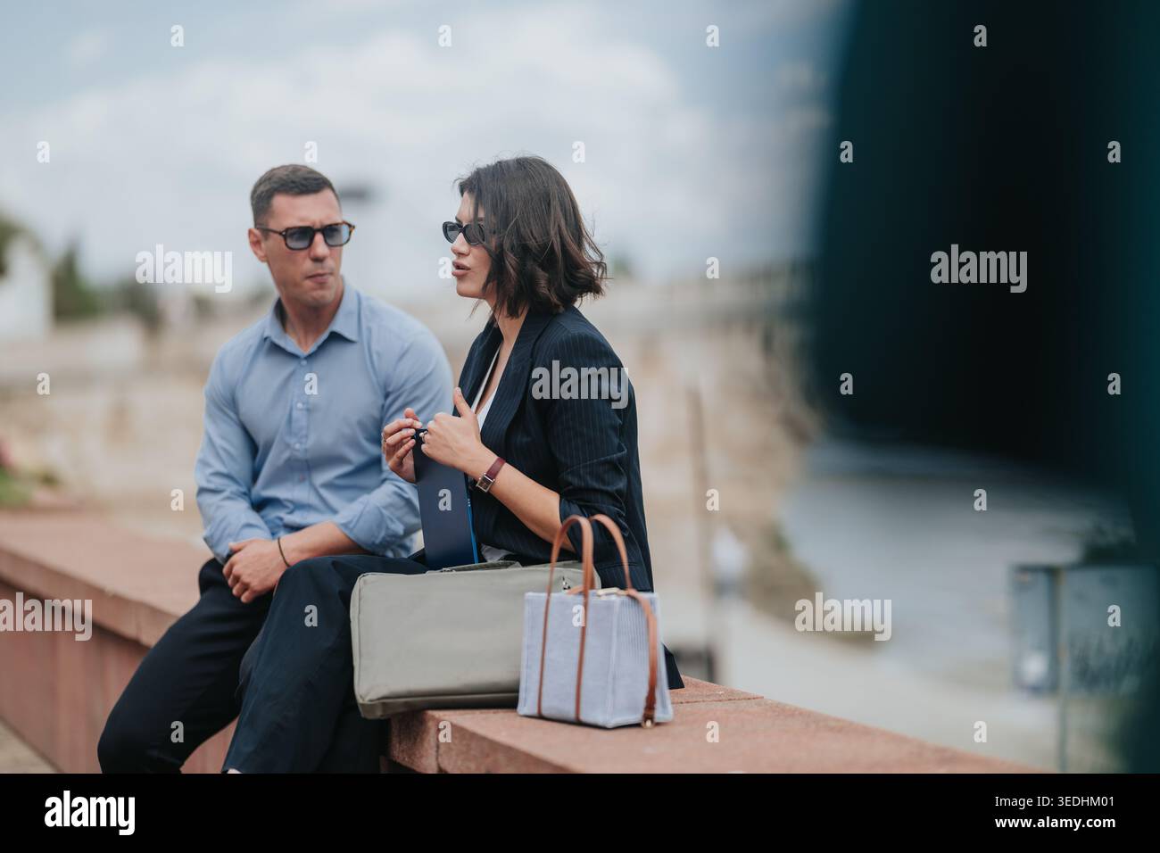 Due persone d'affari sedute sul lungomare che hanno una conversazione professionale durante una pausa Foto Stock