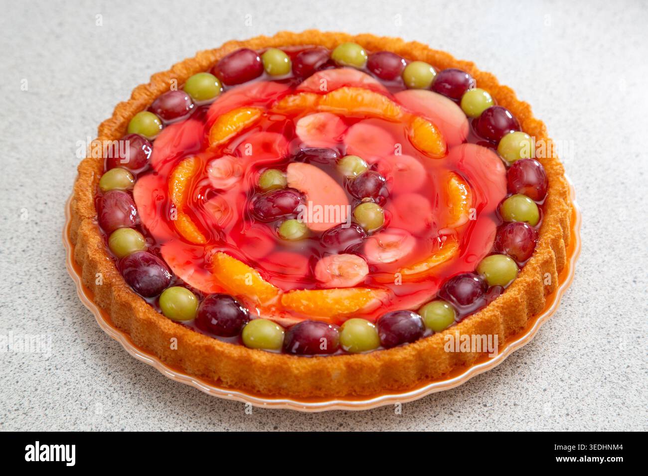 Un flan di frutta, un classico dessert anni '1970 composto da una base leggera di spugna e una colorata disposizione di frutta fresca condita con gelatina Foto Stock