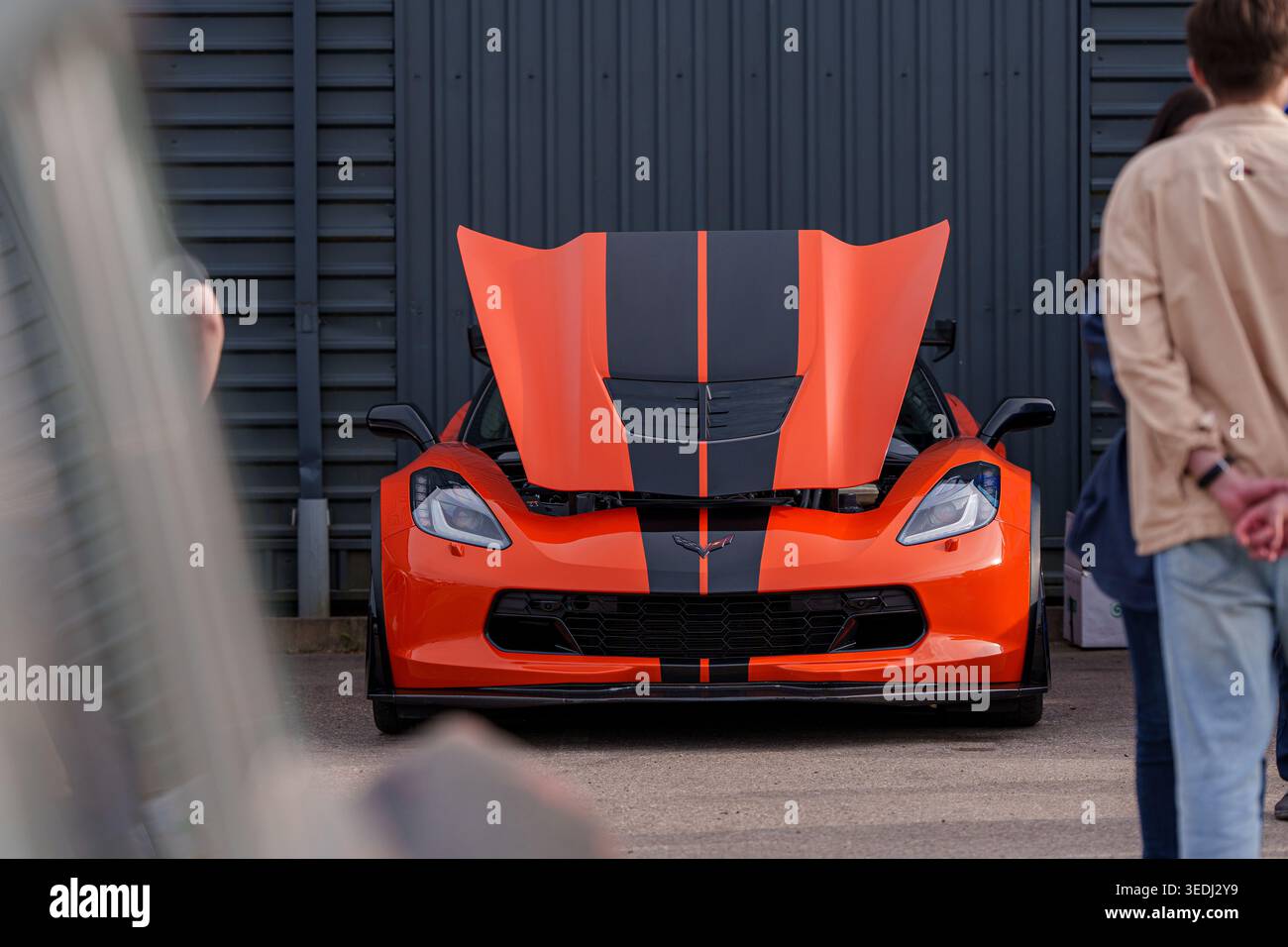 Vista frontale di una Chevrolet Corvette C7 Z06 arancione con strisce da corsa nere e cofano aperto, auto sportiva americana ad alte prestazioni in mostra presso un Foto Stock