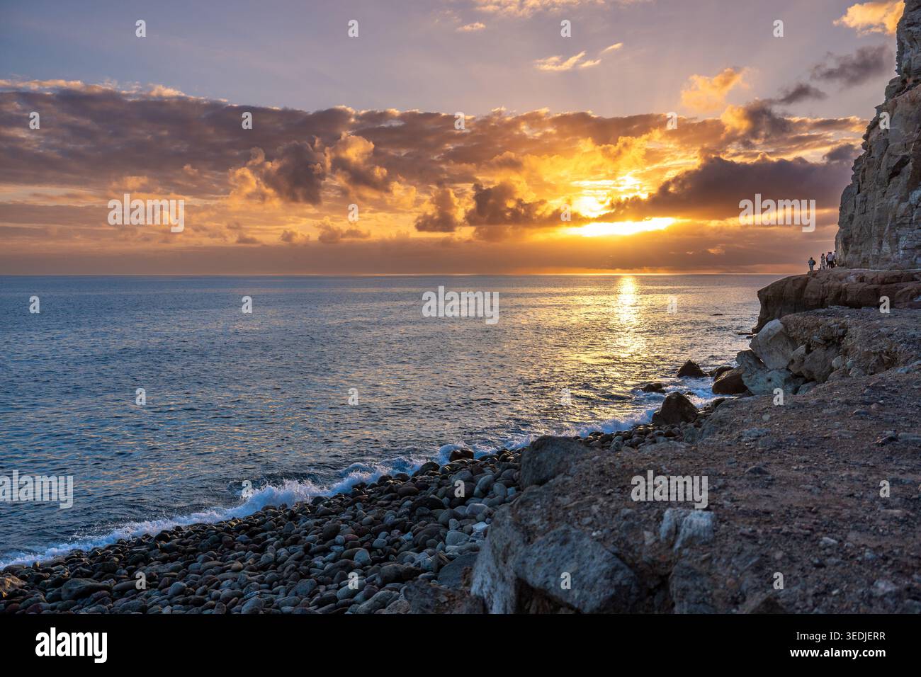 Vista al tramonto della spiaggia di pietra vuota e della costa rocciosa a ovest di Puerto de Mogan Foto Stock