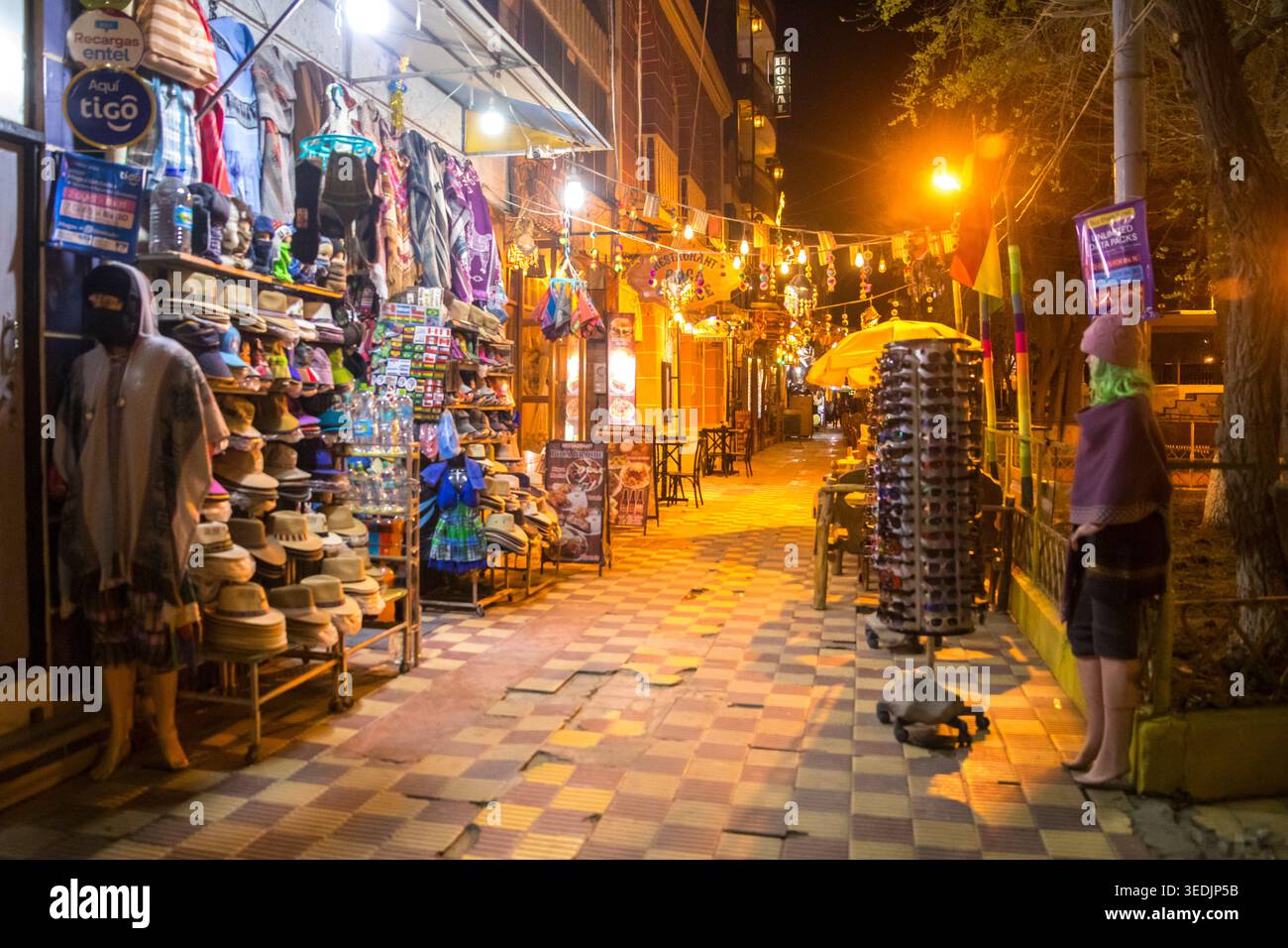 Una vivace strada di mercato all'aperto a Uyuni, Bolivia, si anima di notte, con piccole bancarelle che espongono cappelli, borse, souvenir e go artigianale Foto Stock