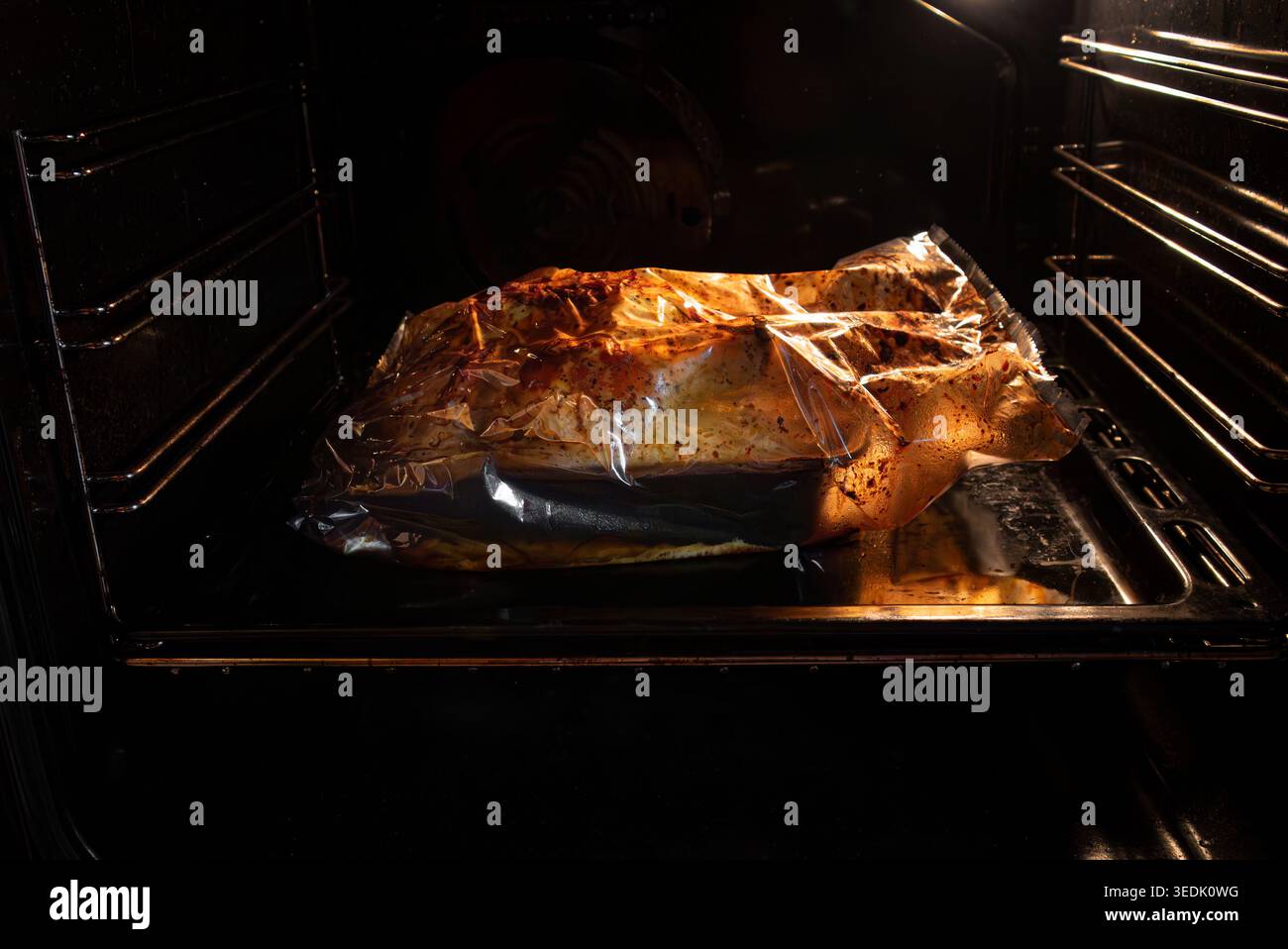 Cuocere il pollo intero in un sacchetto di tostatura all'interno del forno. Foto Stock