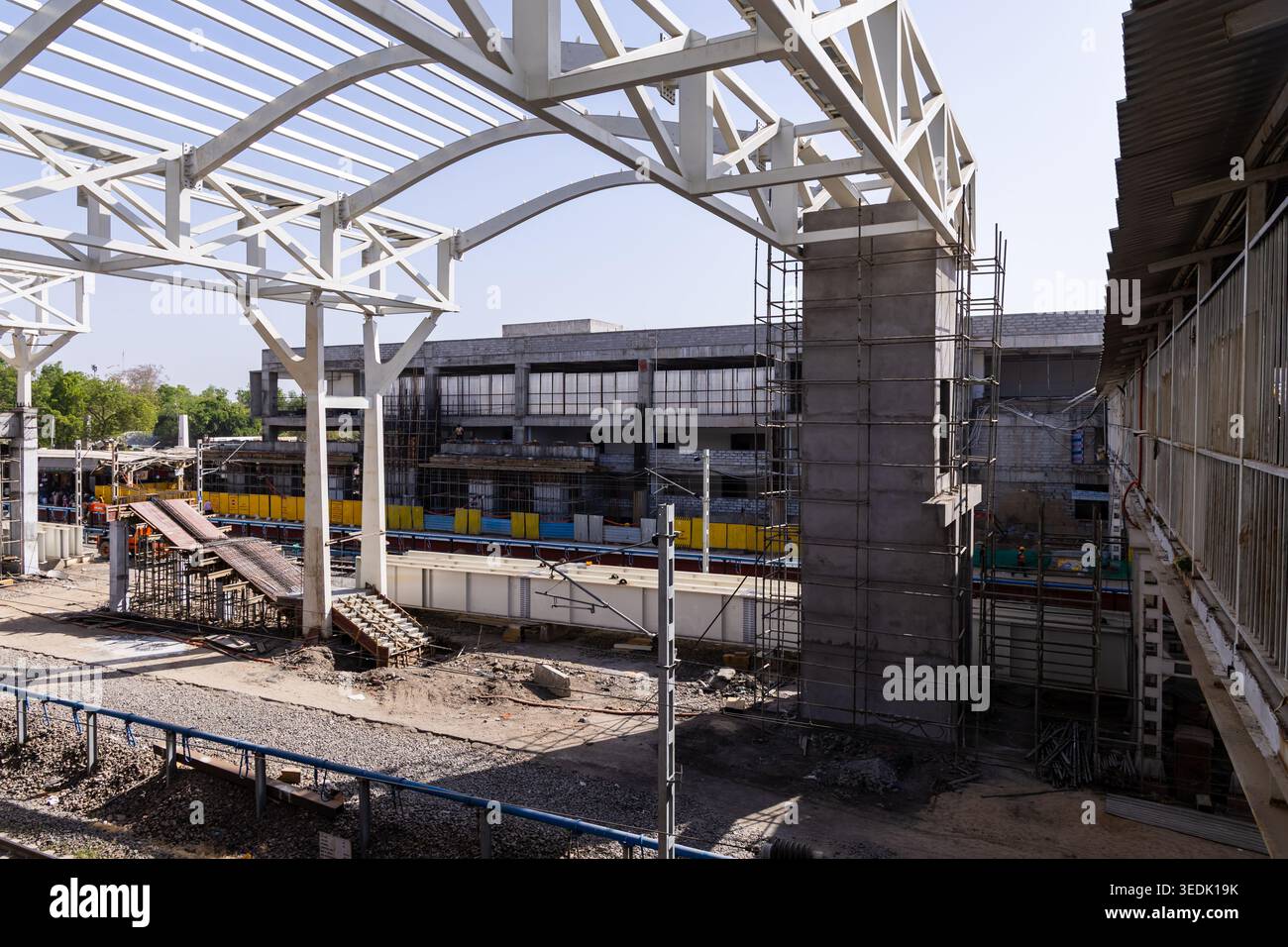 La stazione ferroviaria in costruzione con capriate metalliche e linee elettriche in primo piano viene scattata ad Ahmedabad, gujrat, india, il 10 aprile 2026. Foto Stock