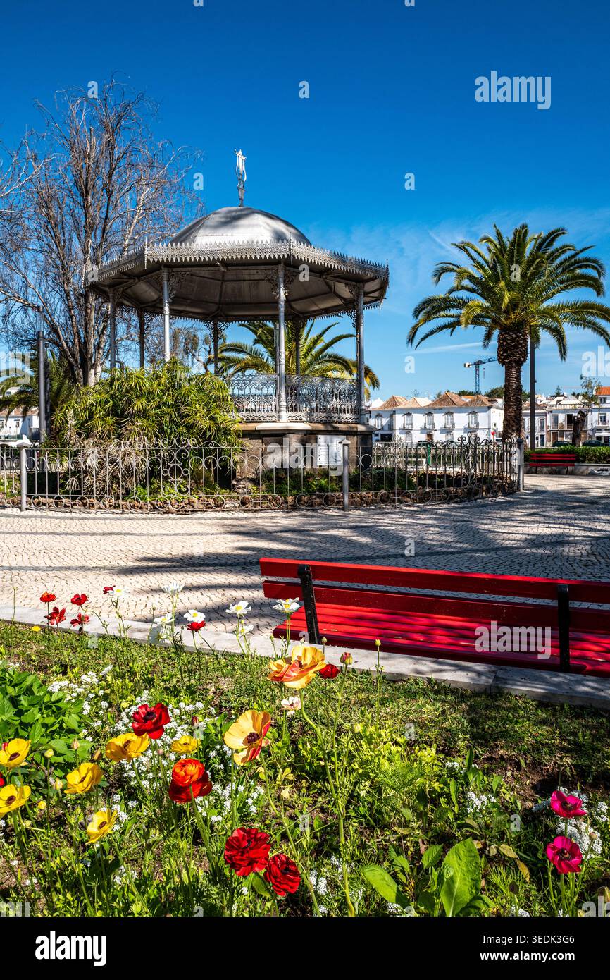 Aiuole colorate e palme in tribuna nei giardini pubblici lungo il fiume Rio Gilão nel centro di Tavira, Algarve, Portogallo Foto Stock
