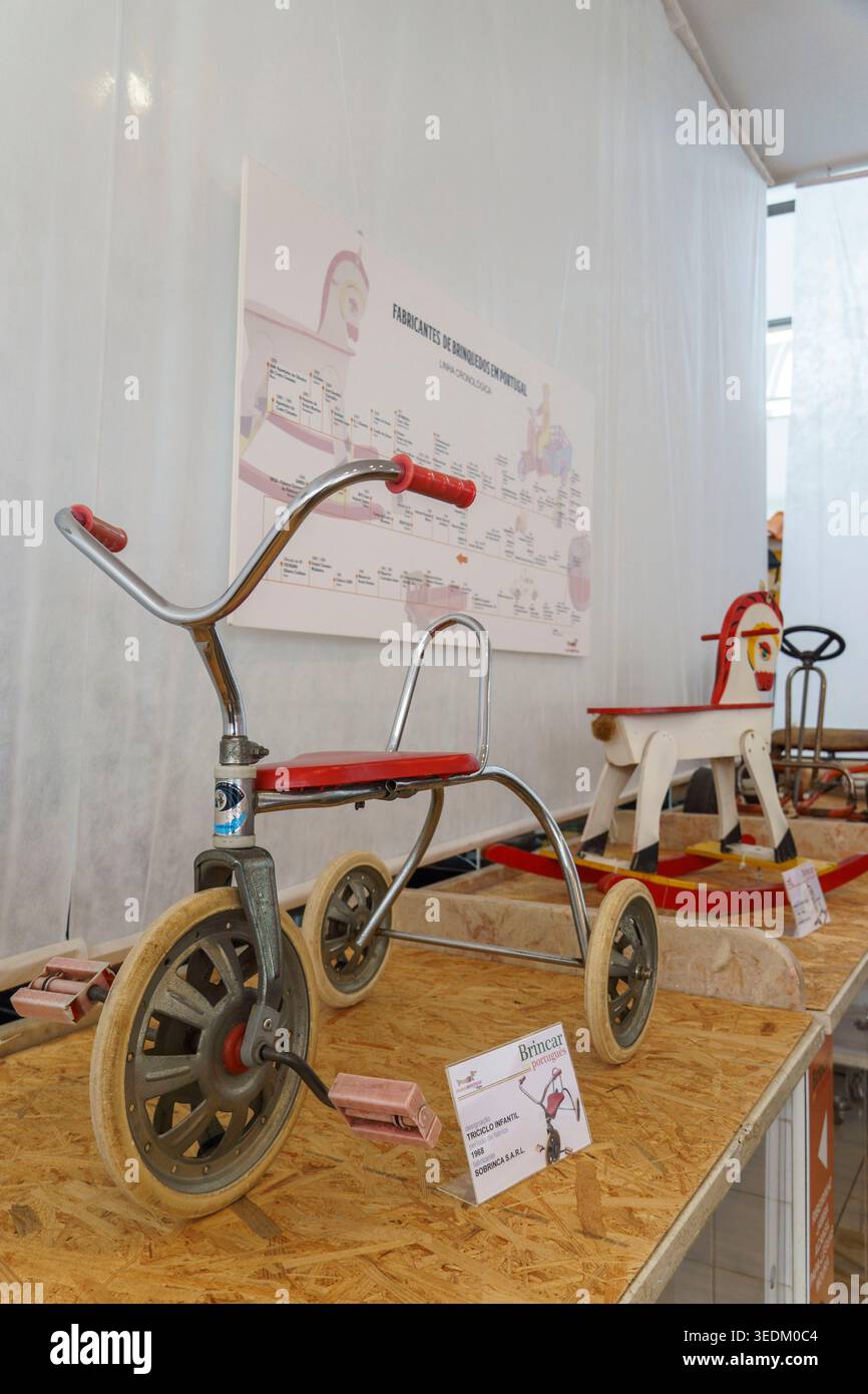 Giocattoli portoghesi d'epoca con triciclo in metallo e un cavallo a dondolo in legno in mostra al museo dei giocattoli Museu do Brincar, Vagos, Portogallo, Europa Foto Stock