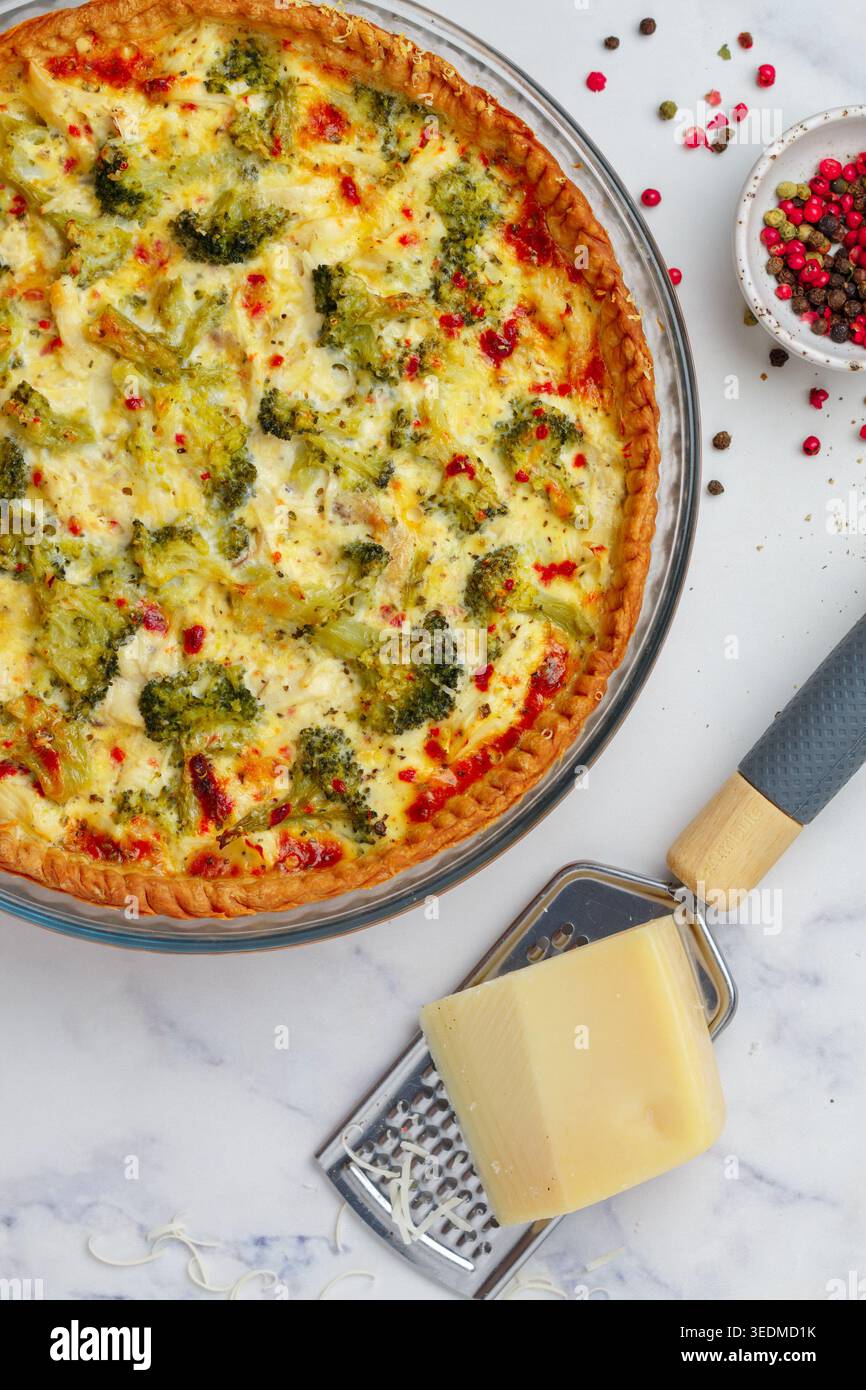 Quiche Lorraine con pollo e broccoli su sfondo in marmo. Torta con verdure, pollame, formaggio, prezzemolo e spezie. Francese tradizionale Foto Stock