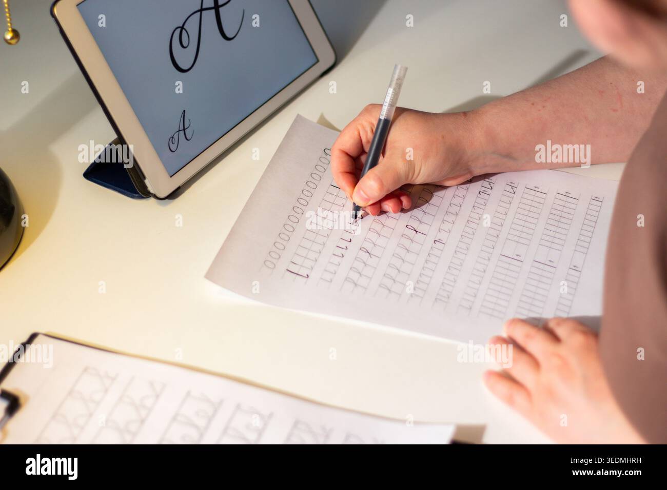 Concetto fisico su digitale. Donna che allena la calligrafia alla scrivania. La scrittura a mano migliora la concentrazione e la comprensione concettuale meglio del digitale Foto Stock