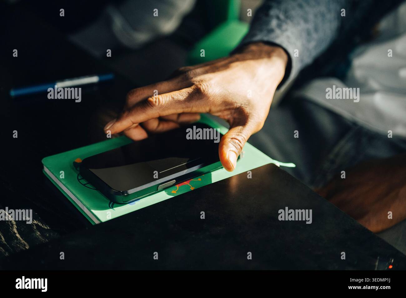 Primo piano di un uomo d'affari che prende lo smartphone dalla scrivania in ufficio Foto Stock