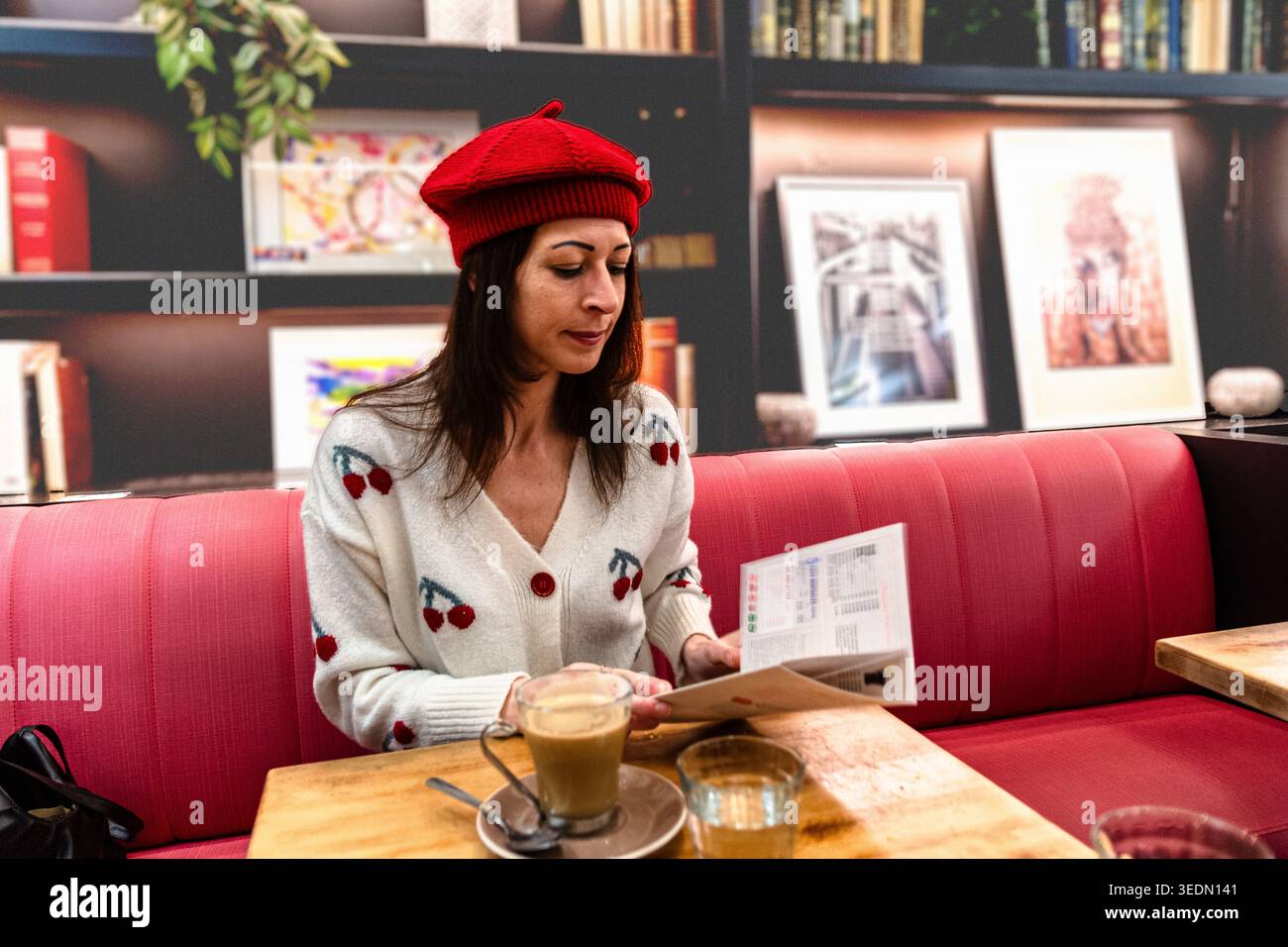 Viaggiatrice da sola che si rilassa leggendo in un bar Foto Stock