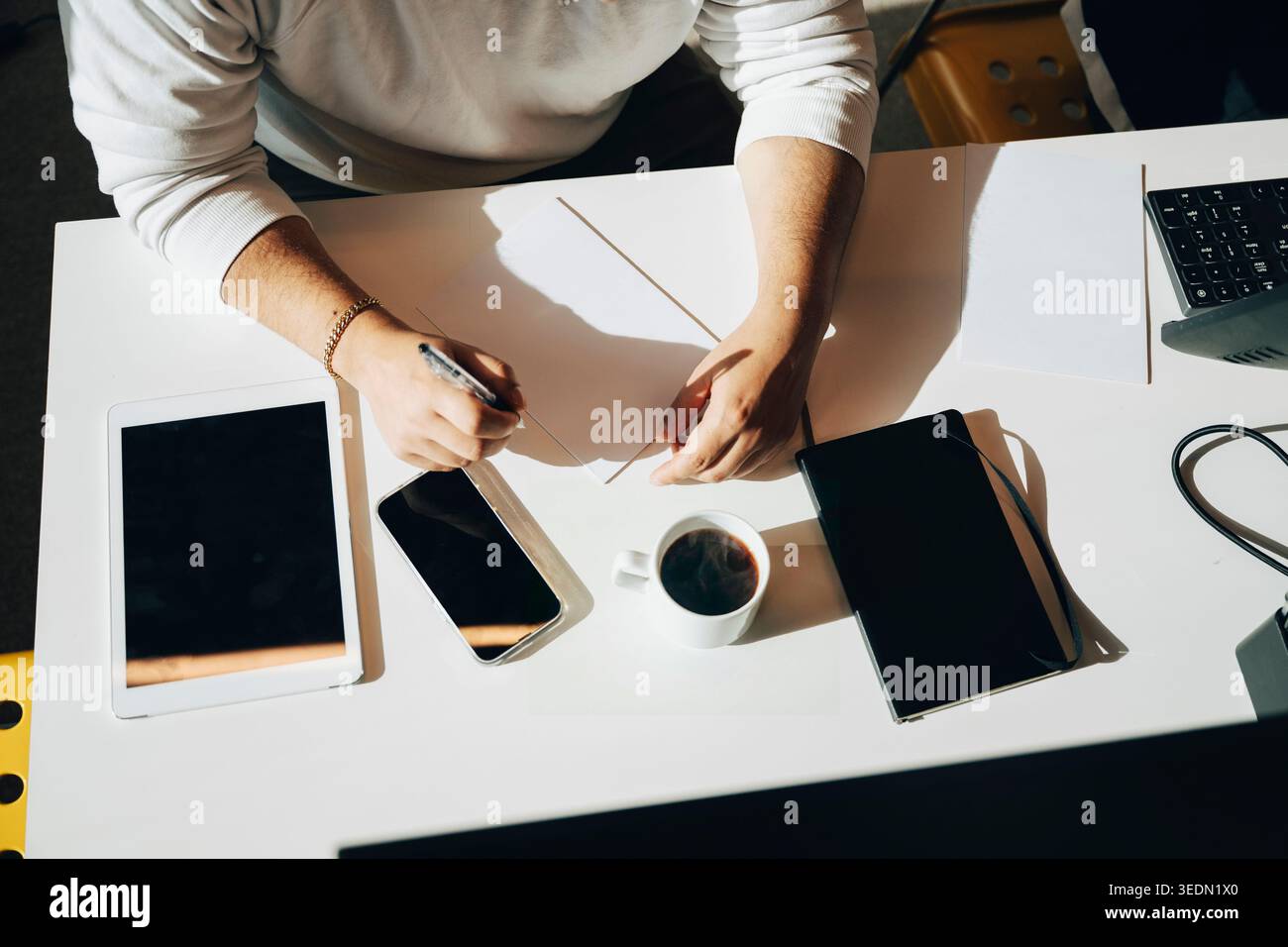 Vista ad angolo alto di un uomo d'affari che scrive appunti su carta alla scrivania bianca Foto Stock