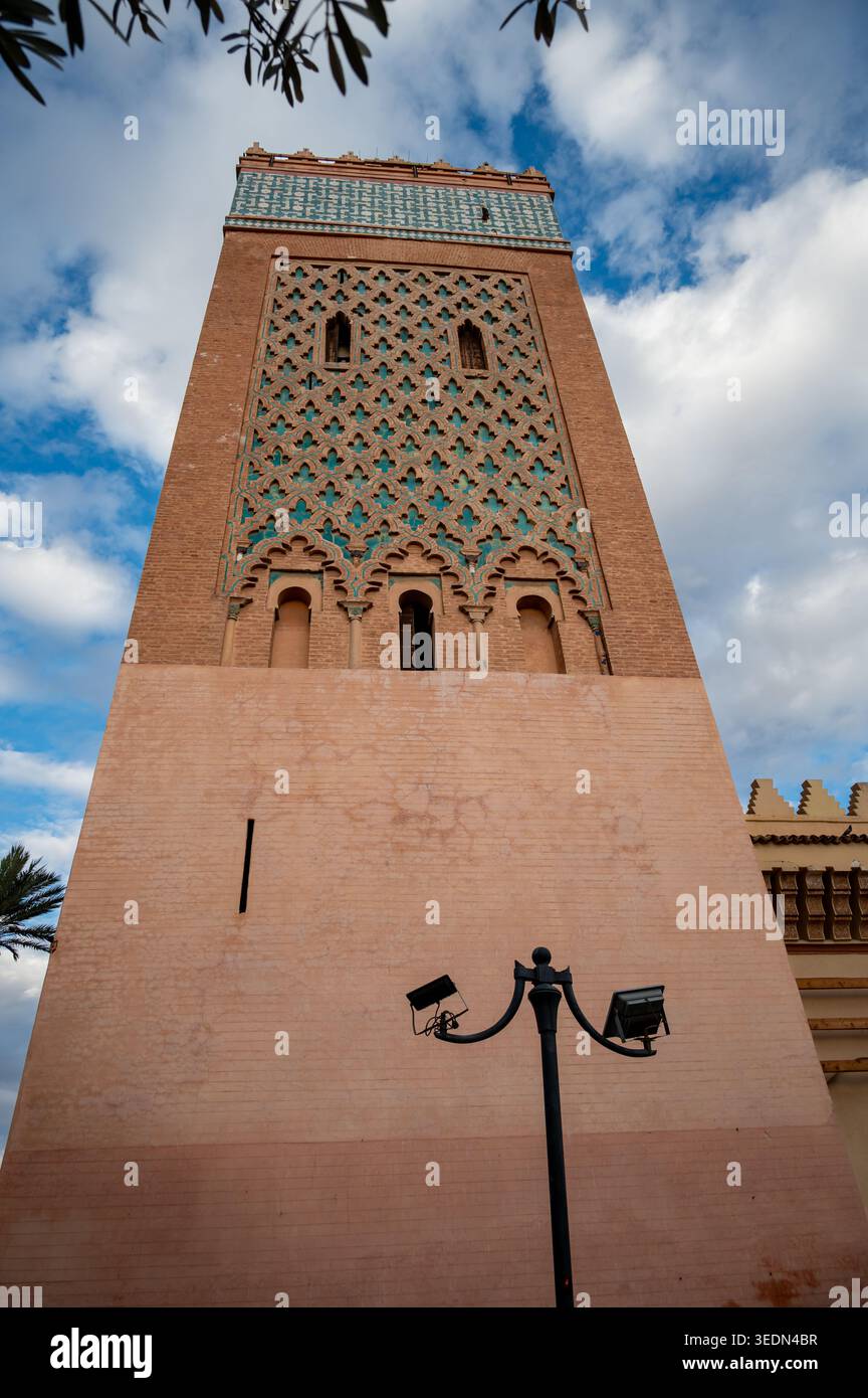 Alto minareto della moschea della Kasbah che si innalza contro un cielo blu a Marrakech, Marocco, mostrando piastrelle geometriche islamiche ornate, architettura in mattoni ocra e. Foto Stock