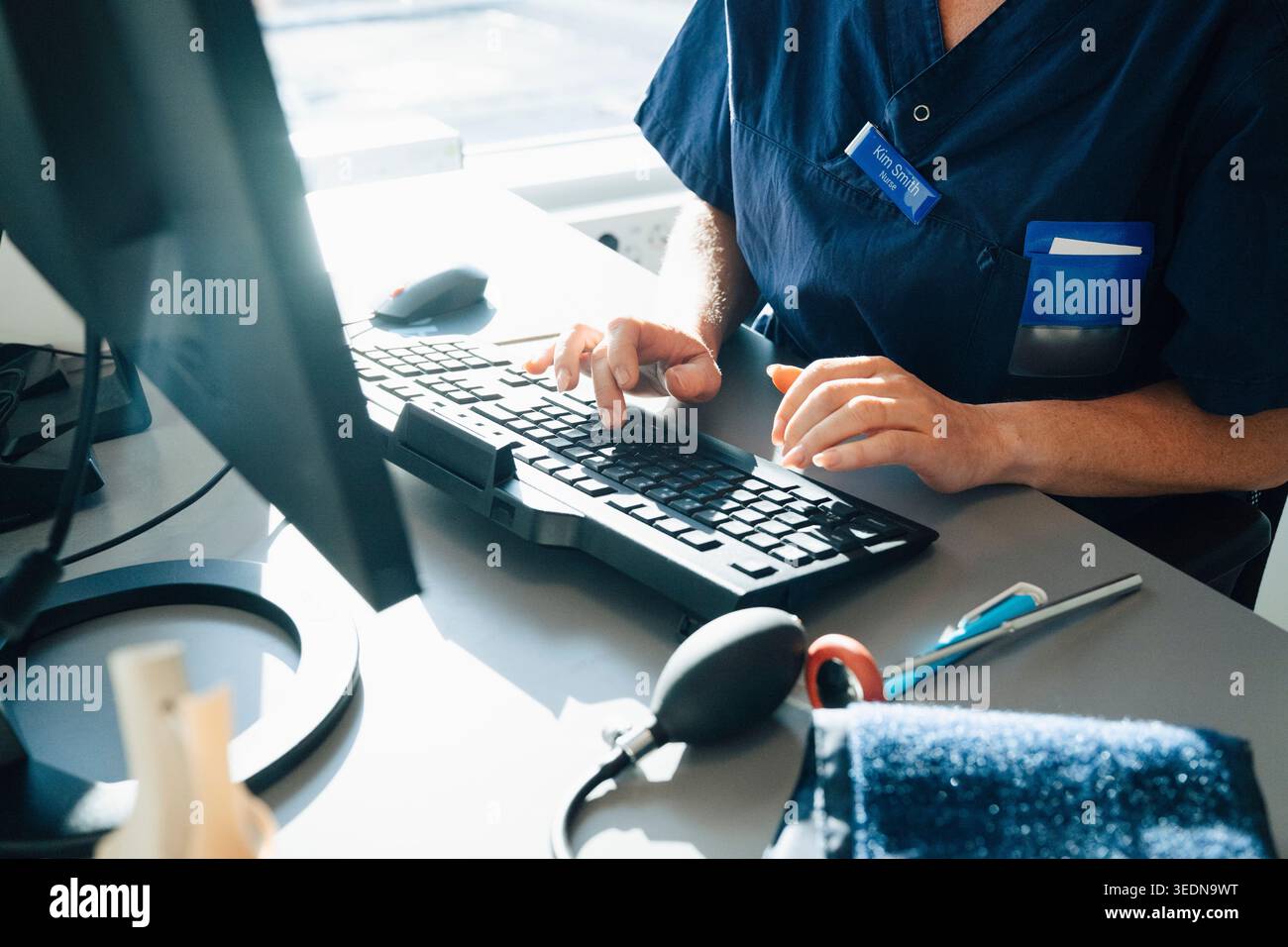 Intersezione di donna medico esperto di digitazione su tastiera durante il lavoro in ufficio ospedaliero Foto Stock